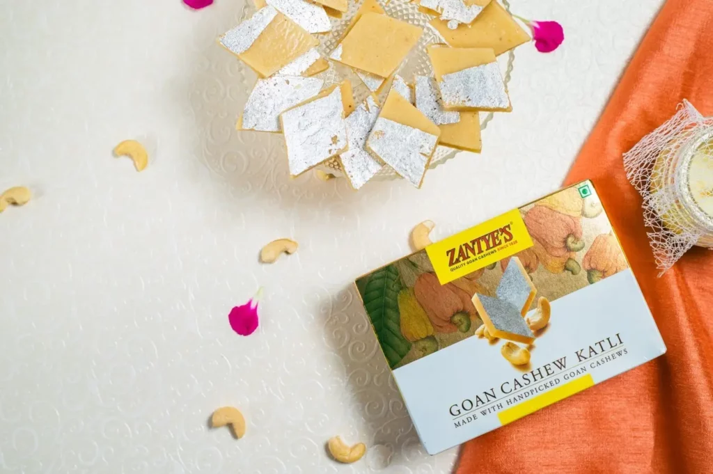 A flat lay of Zantye’s Goan Cashew Katli pack with few pieces layered in a dish.